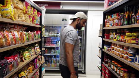 South-Asian,-Indian-Man-is-Browsing-through-Products-in-an-Alley-at-a-Hypermarket-when-Shopping