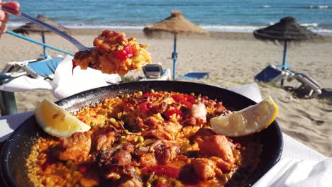 scooping-paella-on-the-beach-with-a-ladle,-summer-vacation-shot,-footage-filmed-in-Marbella,-Spain