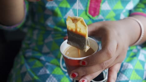 Unrecognizable-girl-dipping-tea-bag-in-cup,-slow-motion-close-up-shot