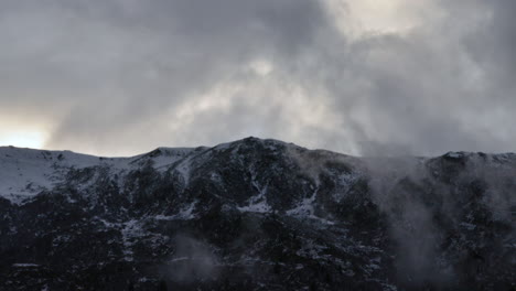 Time-lapse-of-cloud-rolling-past-the-top-of-a-mountain-in-the-French-Alps,-while-looking-dark-and-moody