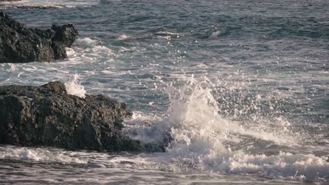 Waves-crash-against-rocks-along-the-shore-and-splash-into-the-air