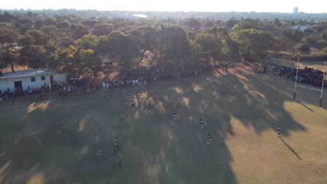 Eine-Diagonale-Einschubaufnahme-Eines-Rugbyspiels-Zwischen-Zwei-High-School-Teams,-Aufgenommen-Bei-Sonnenuntergang