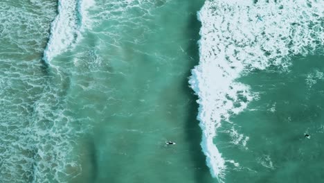 Tracking-shot-of-a-wave-breaking-through-a-group-of-surfers