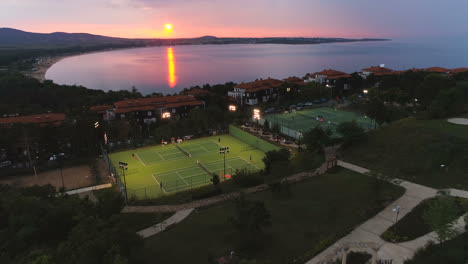 Luftaufnahme,-Rückwärtsgang,-Drohnenaufnahme,-Roter-Sonnenuntergang-Und-Luxuriöse-Tennisplätze,-In-Sozopol,-Schwarzes-Meer,-Bei-Einem-Wunderschönen-Sonnenuntergang