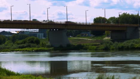 Bridge-time-lapse-of-traffic-passing-by-with-blur-motion-from-under-the-bridge-with-river-and-blue-water