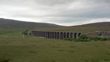 Aerial-Following-Shot-of-a-Northern-Train-Crossing-Ribblehead-Viaduct-in-the-Yorkshire-Dales-National-Park