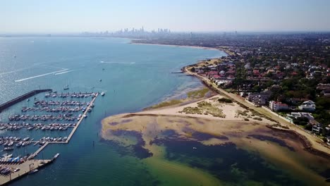 Aerial-view-over-beach-in-Port-Philip-Bay-with-Melbourne-skyline-in-background