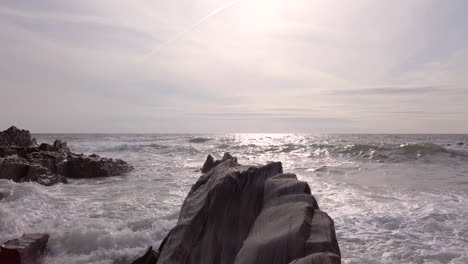 Left-to-Right-Pan-of-Waves-Breaking-Against-a-Rocky-Cove-on-a-Summer’s-Evening-in-Slow-Motion