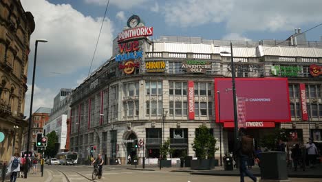 Printworks-tourist-attraction-Greater-Manchester-with-buses-and-people-walking-by-summer-sunny-day-landmark-in-the-city-4K-25p