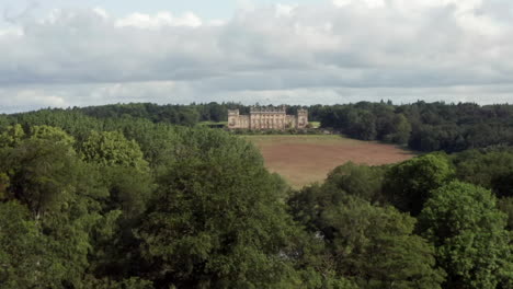 Aerial-Reveal-of-Harewood-House,-a-Country-House-in-West-Yorkshire-with-a-Narrow-Crop