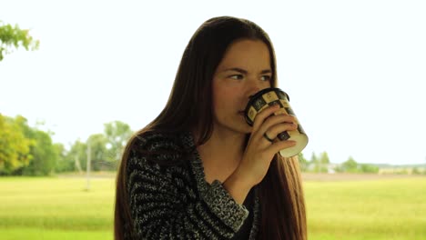 Smiling-girl-drinking-coffee-in-the-nature