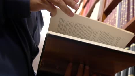 Close-up-low-angle-view-of-a-person-leafing-through-the-pages-of-a-book-in-a-library-or-book-store