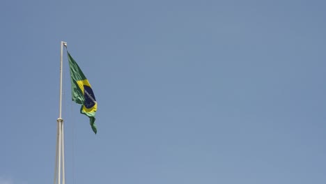 Bandera-Nacional-De-Brasil-Izada-Ondeando-En-El-Día-Del-Cielo-Azul