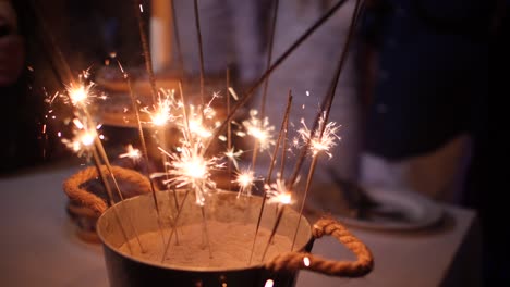 Slow-motion-close-up-on-rustic-decorations-with-many-sparklers-burning-in-a-sand-bucket-at-a-wedding-reception-party