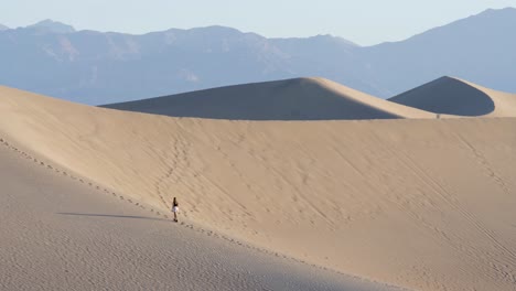 Woman-walking-up-on-steep-sand-dune-in-Death-Valley-National-Park-in-California,-USA---slow-motion