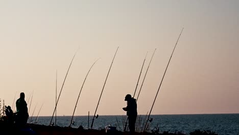 Dos-Pescadores-Parados-En-La-Bahía,-Preparando-Sus-Cañas-De-Pescar