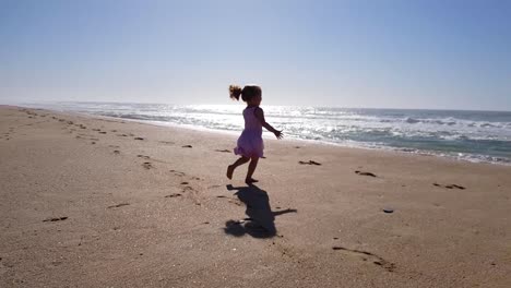 Toddler-girl-running-on-the-beach-towards-the-ocean