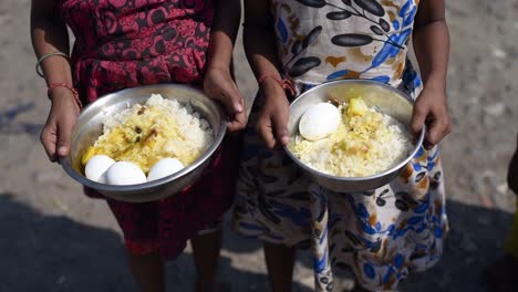 Poor-and-hungry-Asian-children-holding-rice-and-eggs-in-plate-at-sunny-day,-closeup-shot