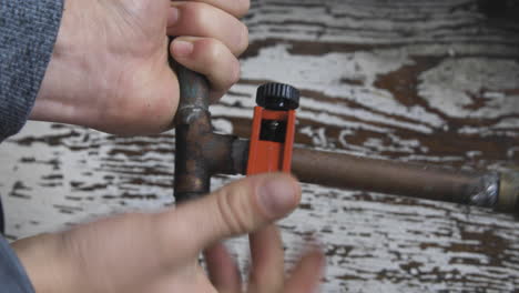An-old-copper-pipe-connection-is-cut-open-by-male-hands-using-a-pipecutter
