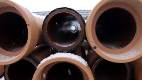 Snow-is-falling-in-winter-time,-as-we-look-inside-some-long-brown-pipes