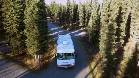 Aerial,-rising,-drone-shot,-of-a-motorhome,-driving-on-a-road-surrounded-by-spruce-forest,-near-Johnson-lake,-in-Kenai-Peninsula-of-Alaska,-United-states-of-america