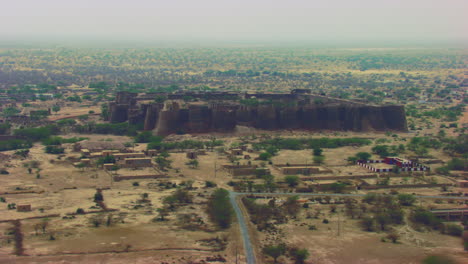 Aerial-flight-over-the-The-historically-significant-Derawar-fort,-Enormous-and-impressive-structure-in-the-heart-of-the-Cholistan-desert,-Located-south-of-the-city-of-Bahawalpur,-Pakistan