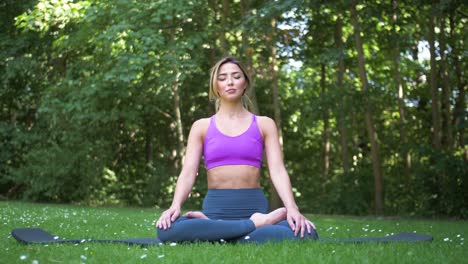 Die-Kamera-Schiebt-Sich-Nach-Rechts,-Während-Eine-Frau-In-Einer-Yoga-Pose-Draußen-Im-Sonnenlicht-Und-Im-Wind-Sitzt-Und-Entspannt-Und-Meditiert