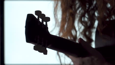 Close-up,-dramatic-style-Long-Red-Haired-man-Playing-acoustic-guitar-silhouette-white-light-background