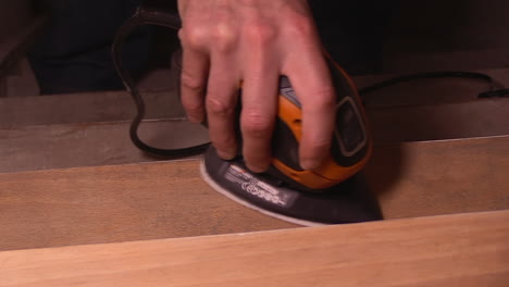 sanding-a-step-on-a-wooden-staircase-with-an-electric-tool