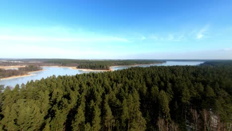 aerial-view-of-a-beautifil-landscape-with-spruce-forest-and-frozen-lakes-in-the-distance,-during-winter-season-,-Poland