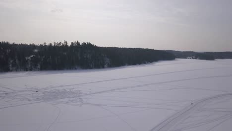 Aerial-shot-slowly-panning-upwards-to-reveal-the-vastness-of-a-frozen-lake-in-the-middle-of-a-forest