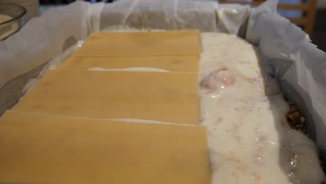 Montaje-De-Lasaña,-Poniendo-Láminas-De-Pasta-Encima-De-La-Salsa-Bechamel