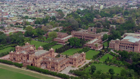 Beautiful-old-college-building-aerial-view-with-city,-Drone-flight-from-side-to-front,-Green-trees-and-forest-with-the-building,-An-imaginary-beautiful-castle-or-emperor-Palace-aerial-view