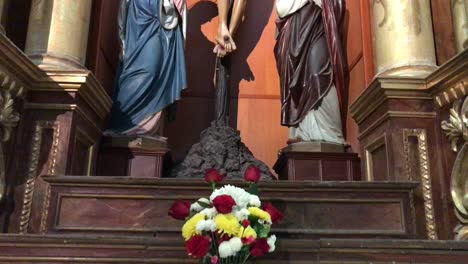 A-bouquet-of-flowers-and-Jesus-on-the-altar-next-to-the-Virgin-Mary,-a-work-of-art