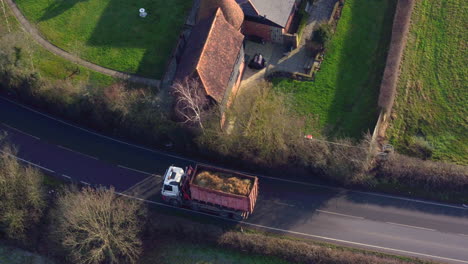Aerial-view-tracking-an-unrecognizable-lorry-along-a-road-carrying-agricultural-materials