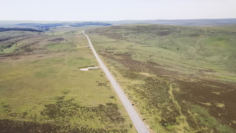Countryside-road-cutting-through-the-Dartmoor-landscape,-aerial-slow-moving
