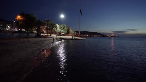 A-Light-Reflects-On-the-Surface-of-the-Water-in-the-Gulf-of-Aqaba-With-a-Huge-Flagpole-in-the-Background