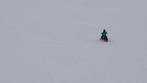 Snowmobile-traveling-on-fresh-snow,-aerial-tracking-shot-4k