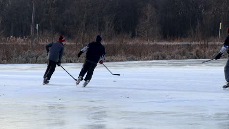Eine-Nahaufnahme-Von-Freunden,-Die-Auf-Einem-Zugefrorenen-Teich-Eishockey-Spielen
