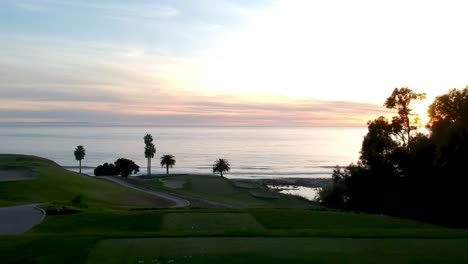 Luftaufnahme-Des-Golfplatzes-Mit-Meerblick-Bei-Sonnenuntergang