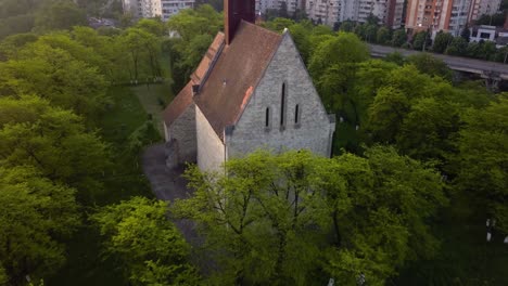 Round-View-Of-Beautiful-Church-between-trees-forest-And-View-of-monument-Town-Cluj,-Romania,-Transylvania