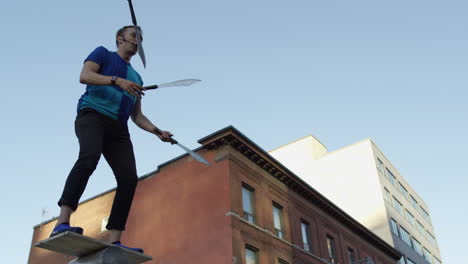 Juggler-in-city-using-swords-in-slow-motion