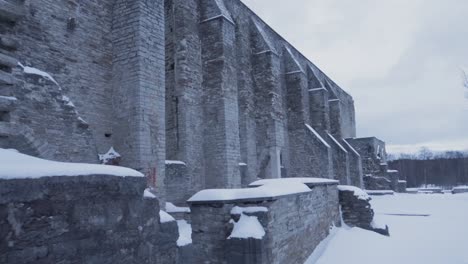 Muro-De-Piedra-En-Las-Antiguas-Ruinas-Del-Convento-Cubierto-De-Nieve-Durante-El-Día-Nublado,-Siguiendo-El-Tiro-Derecho