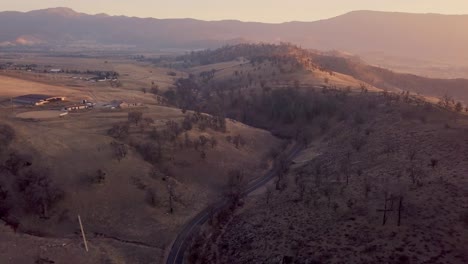 Aerial-pull-back-of-winding-road-in-California-Tehachapi-mountains-at-sunrise