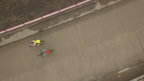 Aerial-top-view-of-two-cyclist-peddling-over-the-dam-at-Colibita-Dam-in-Romania-during-Tura-Cu-Copaci-race