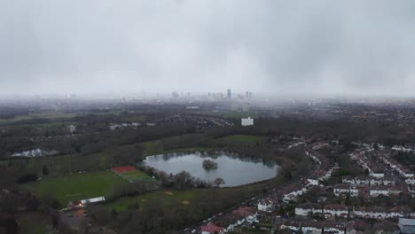 Aerial-London-approach-with-lake-beneath,-misty-and-moody