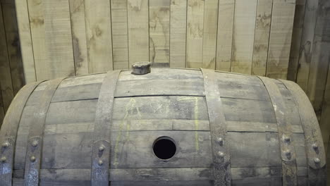 Close-up-of-a-disused,-empty-oak-Scotch-whisky-barrel-on-it's-side-with-a-cork-resting-on-the-top-under-artificial-light