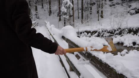 Someone-pulls-an-axe-over-a-railing-with-snow-on-it-which-falls-down