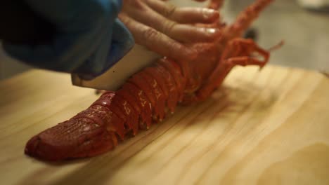 SLOWMO---Close-Up---Cutting-down-through-a-cooked-New-Zealand-crayfish-to-split-it-in-halves-on-a-wooden-cutting-board
