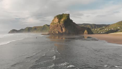 Incredible-aerial-drone-shot-over-black-sand-Piha-Beach-in-New-Zealand-during-sunset